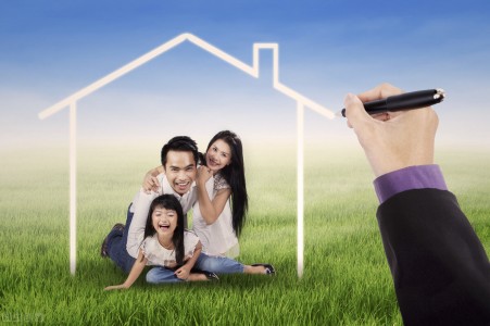 Cheerful asian family laughing together on the meadow under a dream house